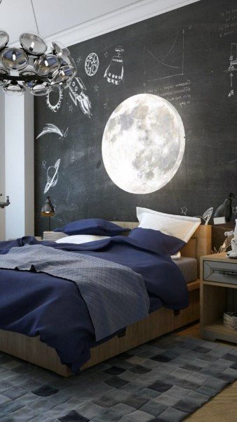 Bedroom with a moon mural on a chalkboard wall, navy bedding, and a modern ceiling light fixture