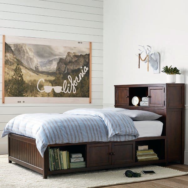 Cozy bedroom with a wooden bed, blue striped bedding, and a "California" landscape poster on the wall