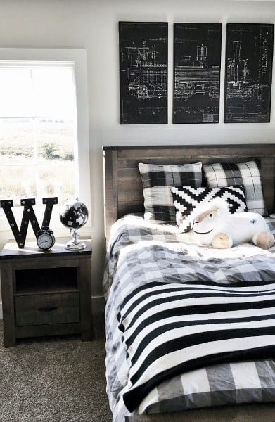 Black and white bedroom with plaid bedding, wooden bed, and decorative wall art.