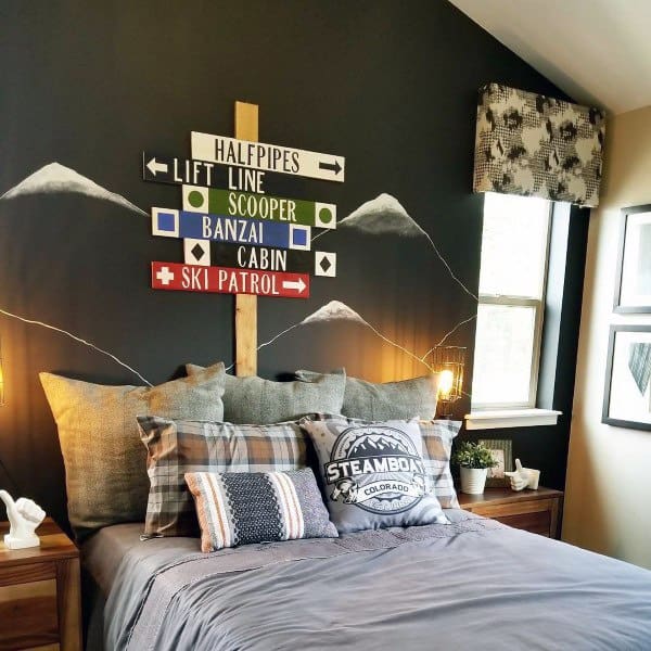 Cozy bedroom with mountain-themed decor and a ski signpost on a dark wall above a bed with plaid pillows