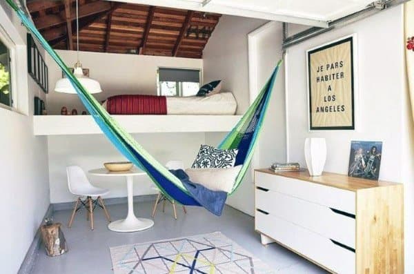 Green and blue hammock in a modern bedroom with loft bed, wooden ceiling, and cozy decor.