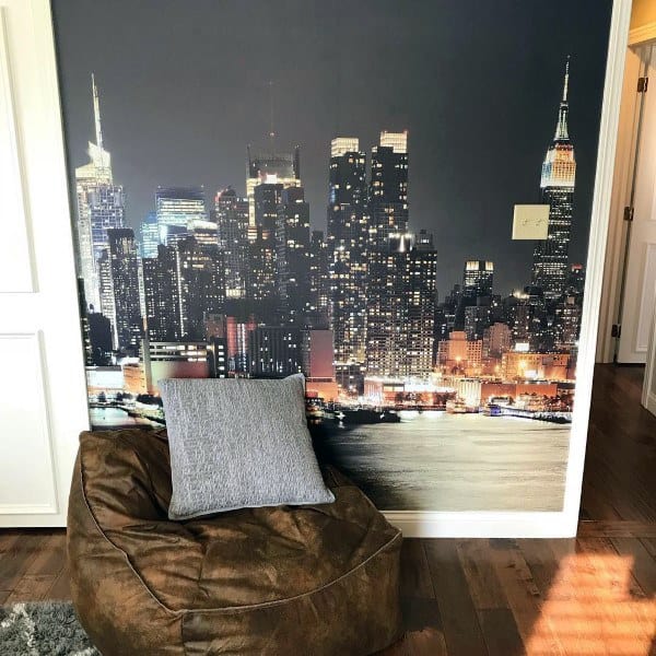 Living room corner with a large cityscape mural, a brown bean bag chair, and a gray pillow on a wooden floor