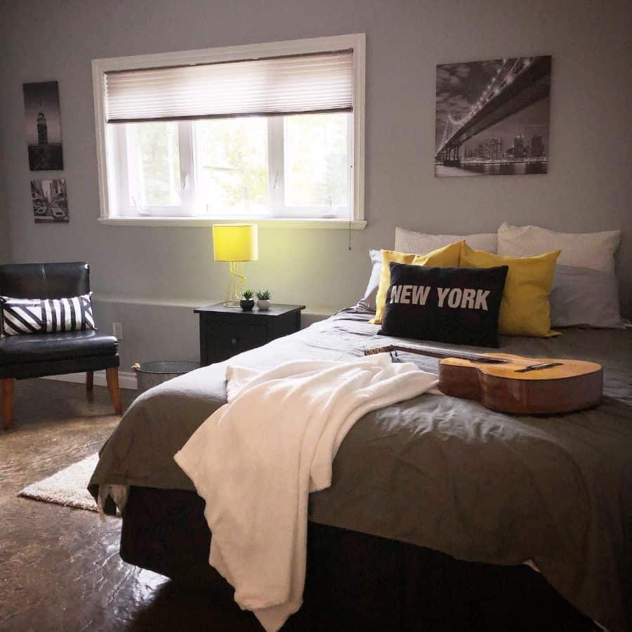 Simple bedroom with New York pillow, yellow accents, and large window for natural light.