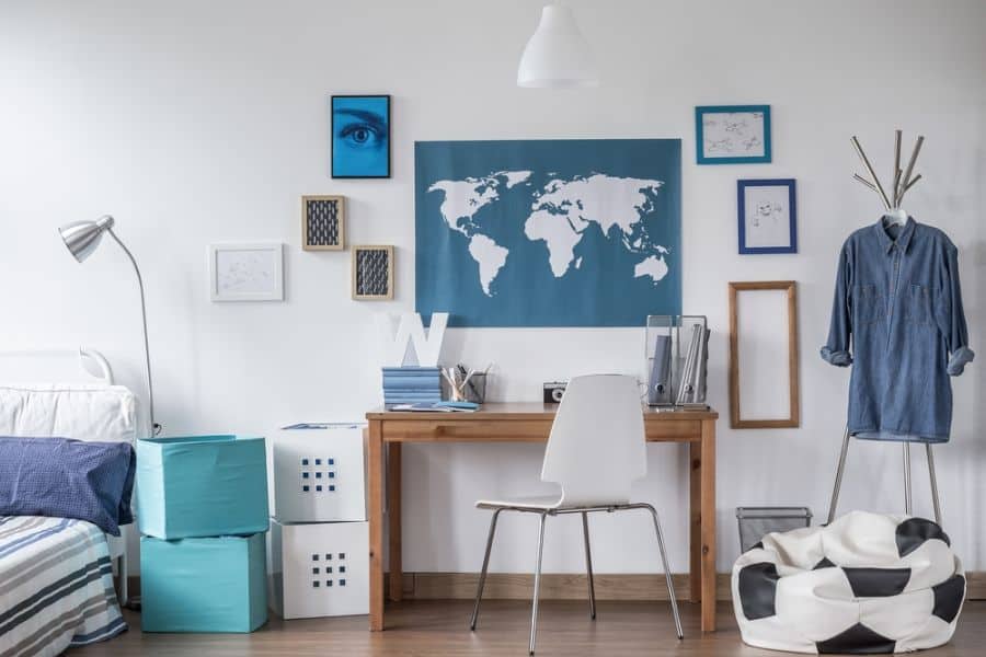 Boy’s bedroom with wood desk, world map wall art, and storage boxes.