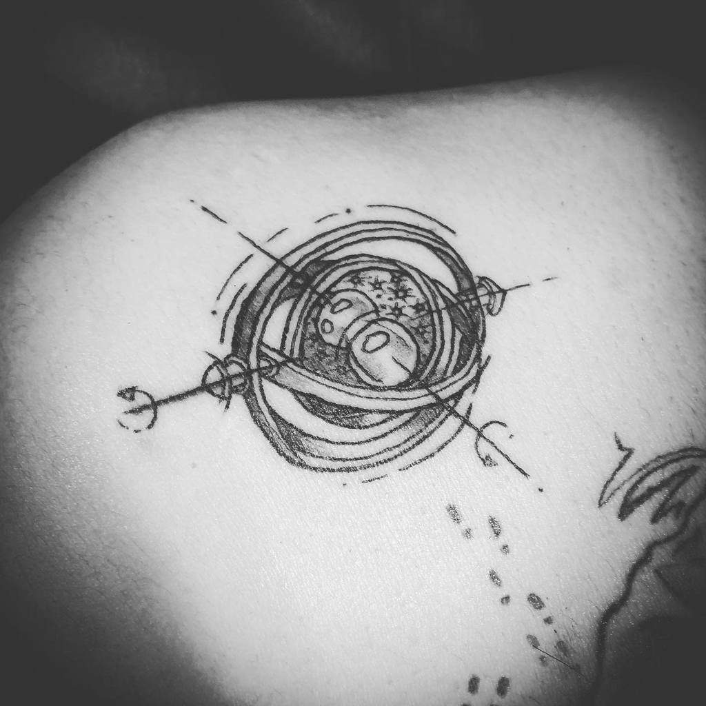 Minimalist Harry Potter tattoo of the Time-Turner, featuring intricate line work and celestial details