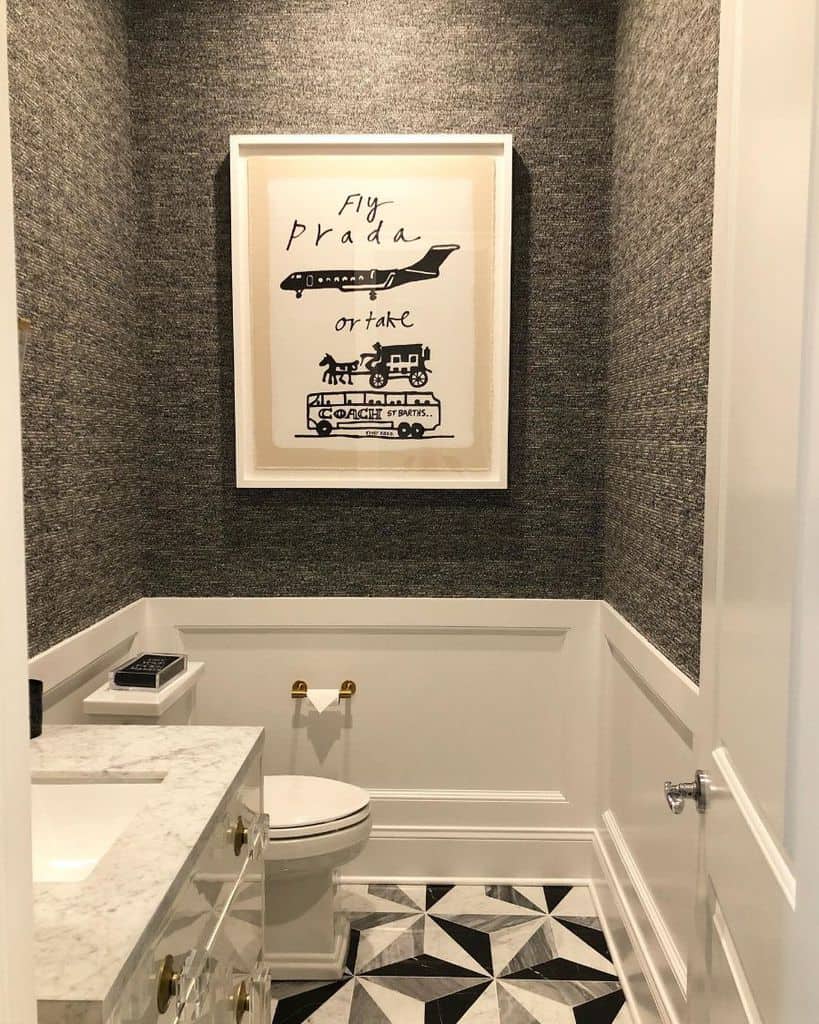 Small bathroom with gray textured wallpaper, framed wall art, and geometric floor tiles.