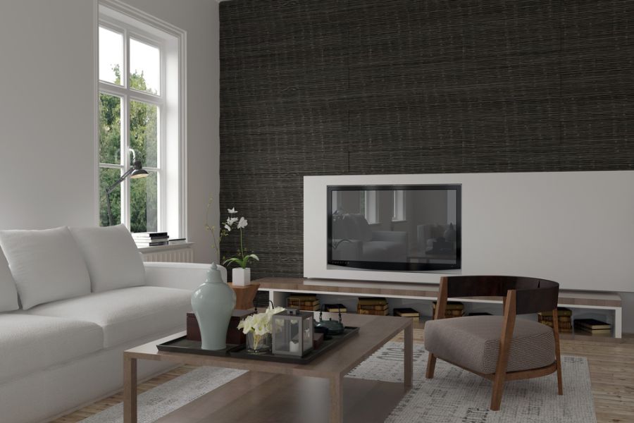Modern living room with white sofa, TV, wooden coffee table with decor, and large window view featuring an accent wall