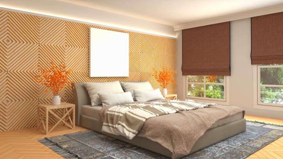 Modern bedroom with a geometric wooden accent wall, cozy bed, orange flowers, and large windows with brown blinds