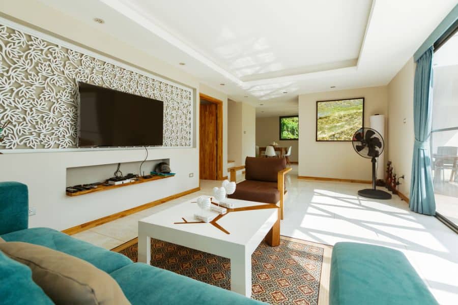 Modern living room with blue sofa, TV on accent wall, and large windows letting in natural light