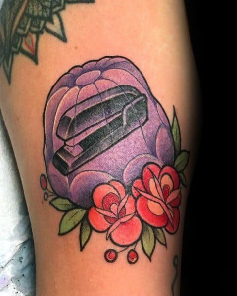 Color tattoo of a black stapler encased in purple Jell-O, surrounded by flowers, referencing Jim’s classic prank on Dwight from *The Office*.