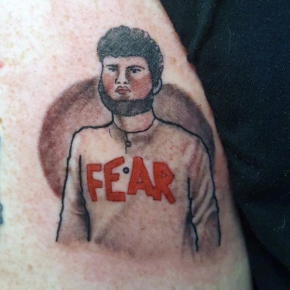 Color tattoo of Mose Schrute from *The Office*, wearing his iconic "FEAR" sweatshirt, referencing his quirky and unsettling presence on Schrute Farms.