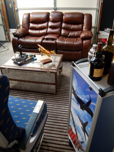 Room with leather recliners, model airplane on a coffee table, and an airplane-themed minibar