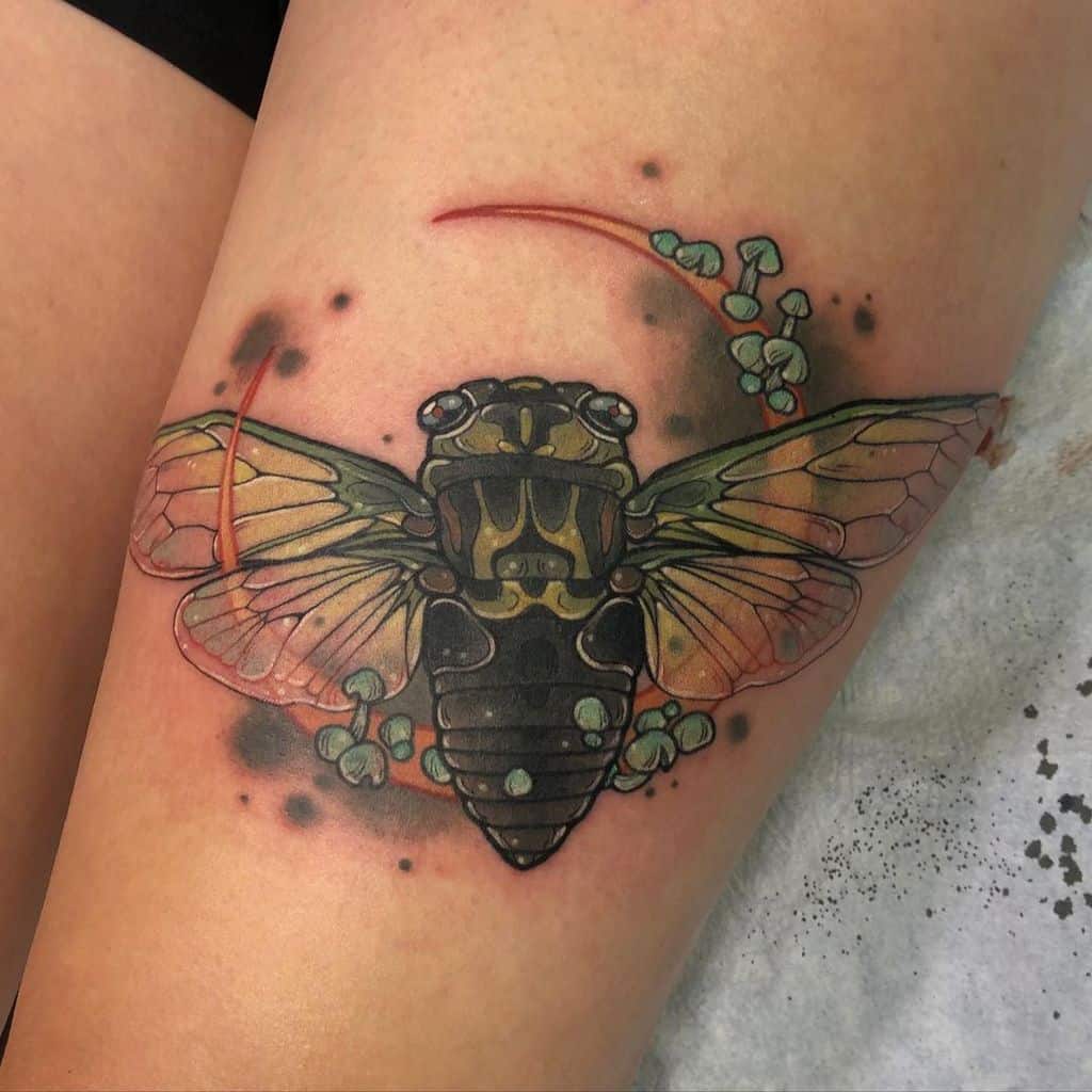 Tattoo of a colorful cicada with decorative elements on a thigh
