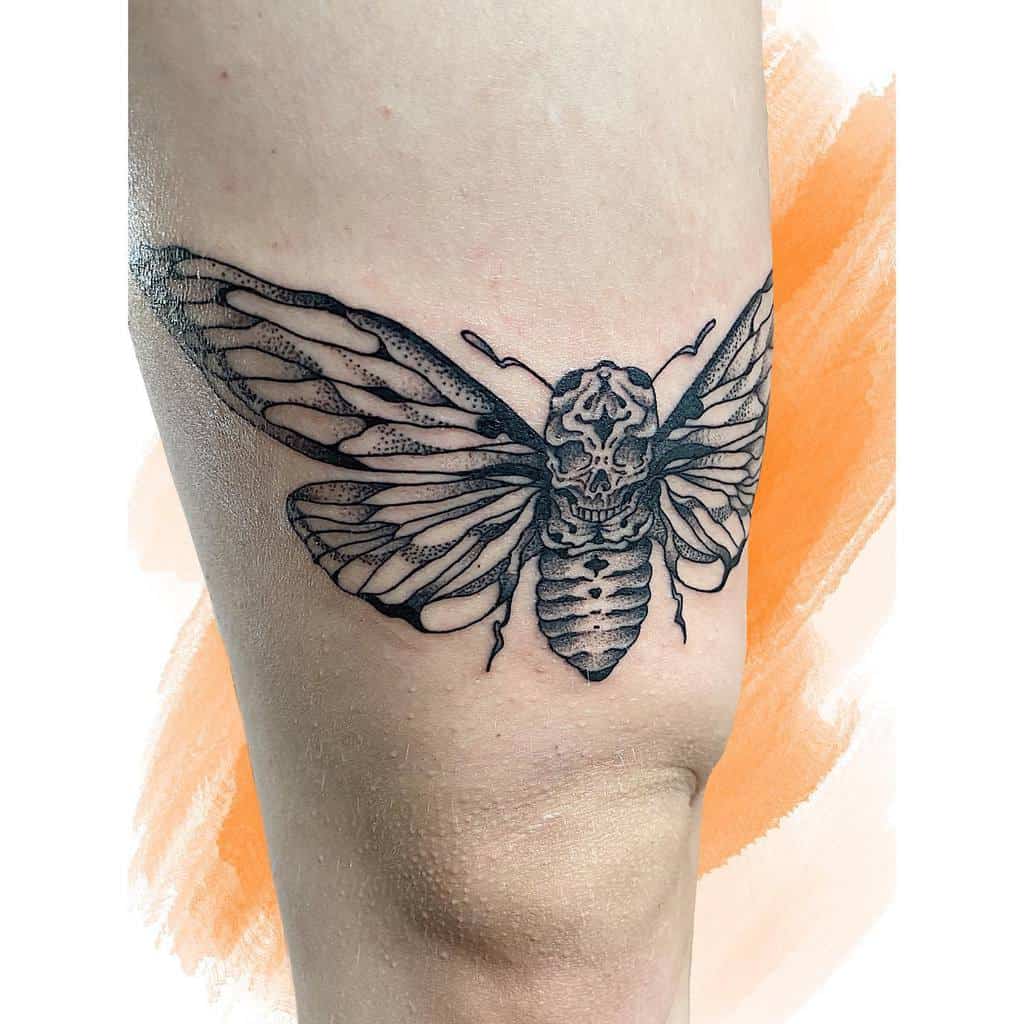 Tattoo of a cicada with a skull design above the knee