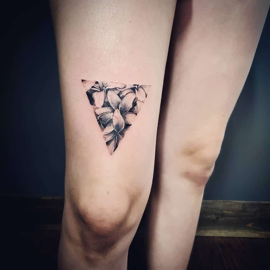 Triangle floral plumeria tattoo on an upper thigh