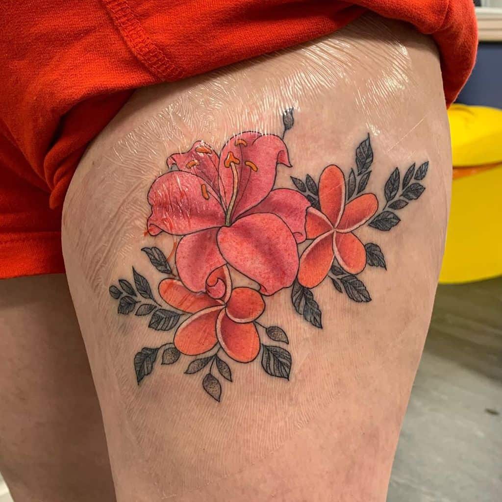 Vibrant thigh tattoo of red hibiscus and plumeria flowers with green leaves, detailed in a bold and colorful style