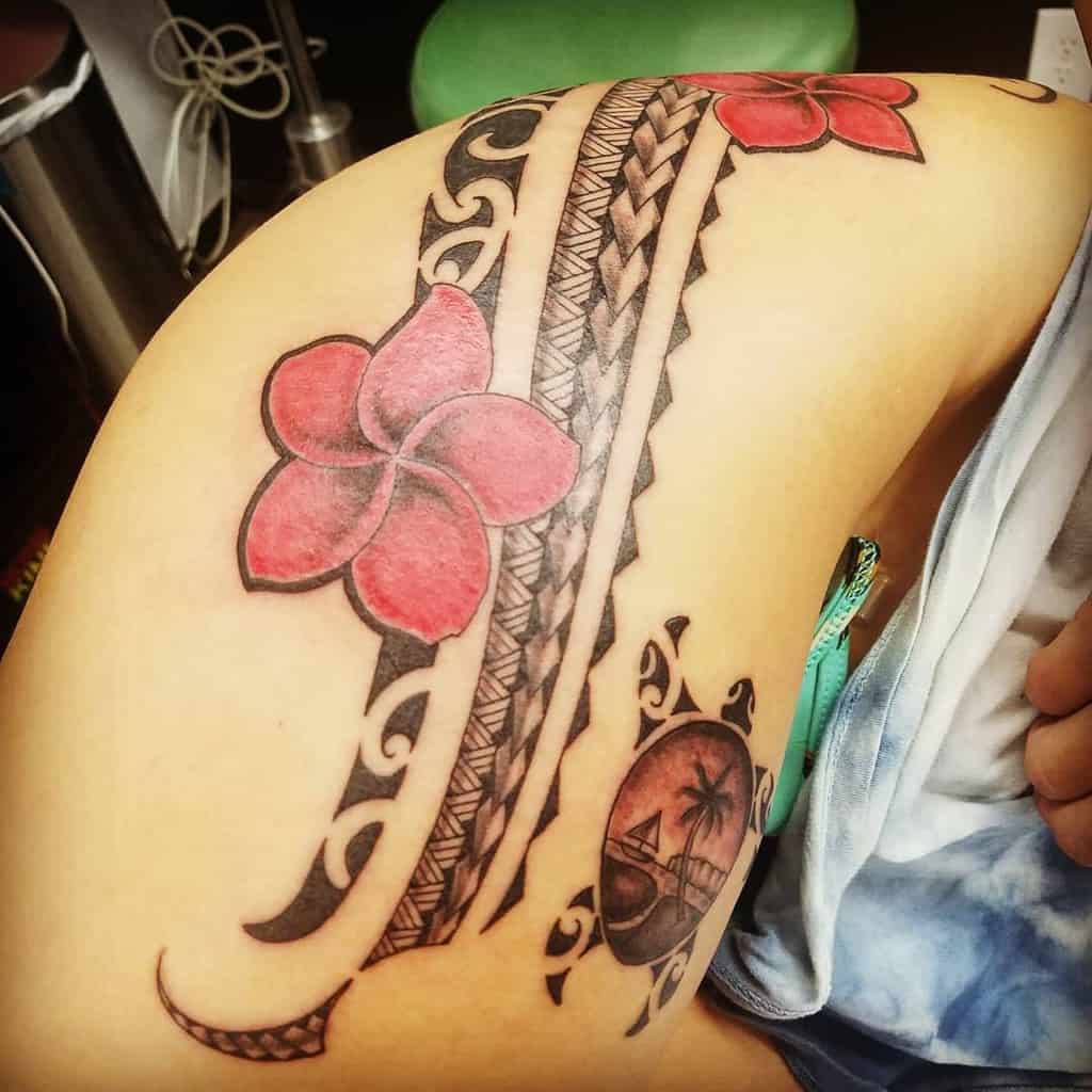Tattoo of plumeria flowers and tribal patterns on a shoulder