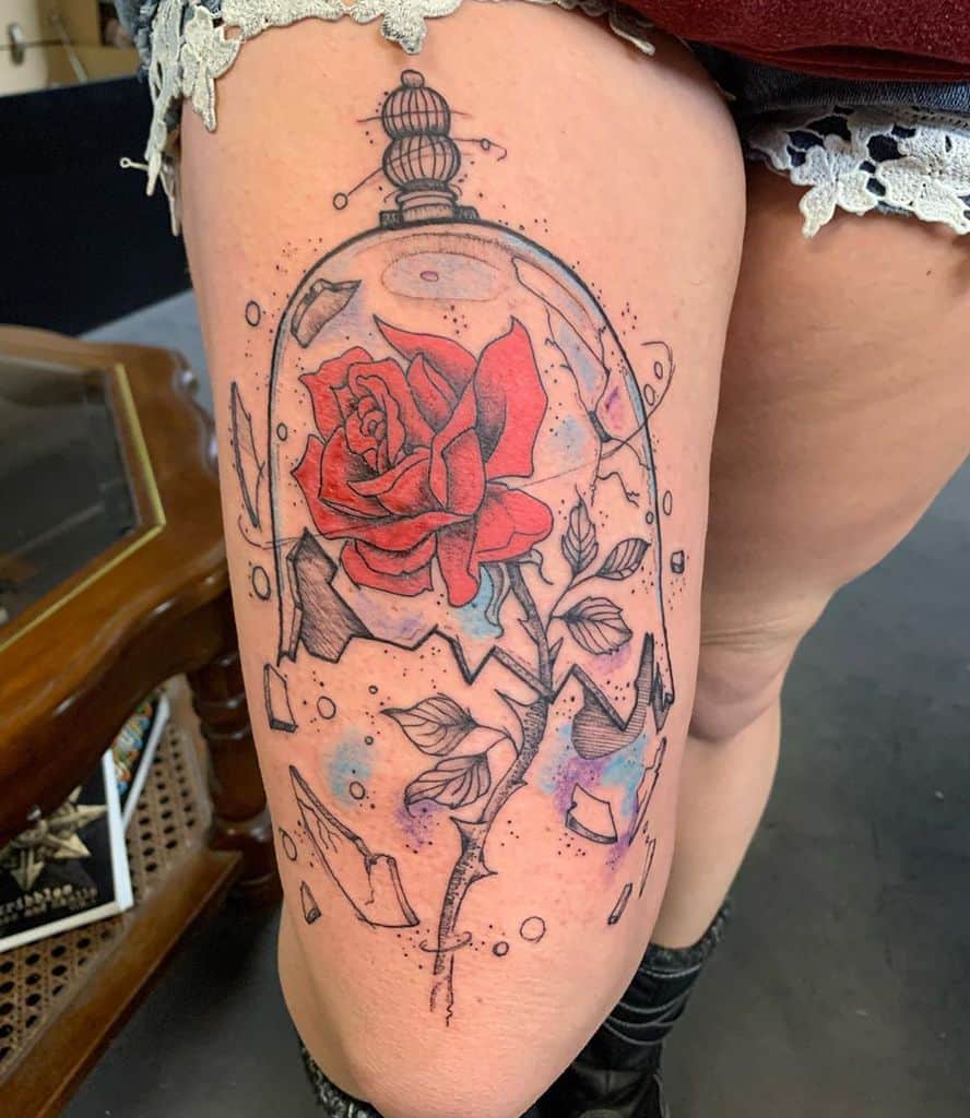 Tattoo of a red rose inside a shattered glass dome on an upper leg