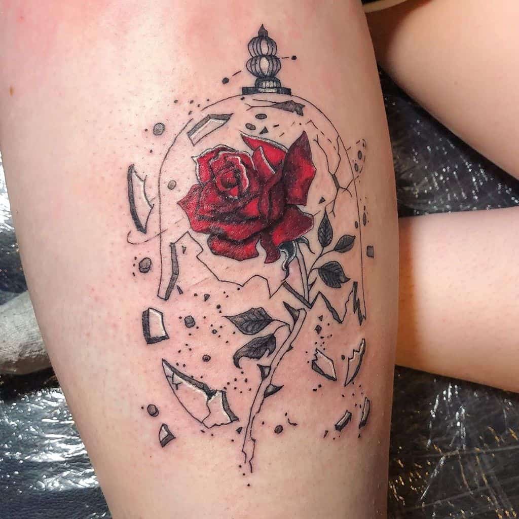 Thigh tattoo of a red rose encased in cracked glass with shattered pieces around it