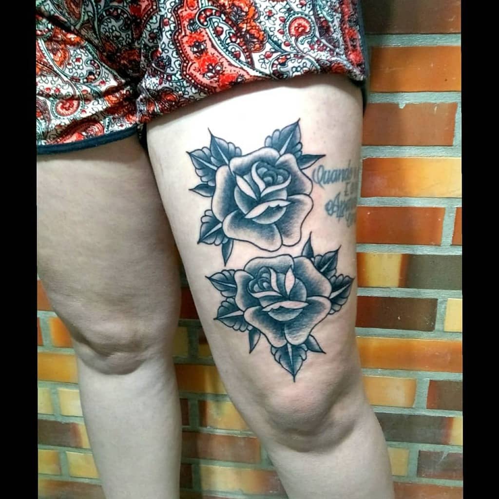 A stunning black and white tattoo of two roses blooms elegantly on a thigh