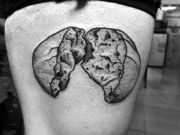 Black and gray tattoo of a round loaf of bread split in half, featuring fine shading and texture to highlight the crust and soft interior.