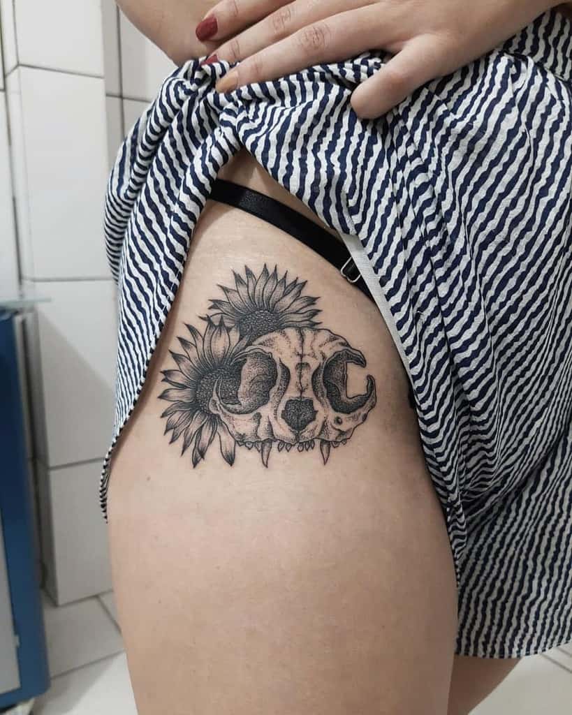 Thigh tattoo of a detailed cat skull adorned with sunflowers