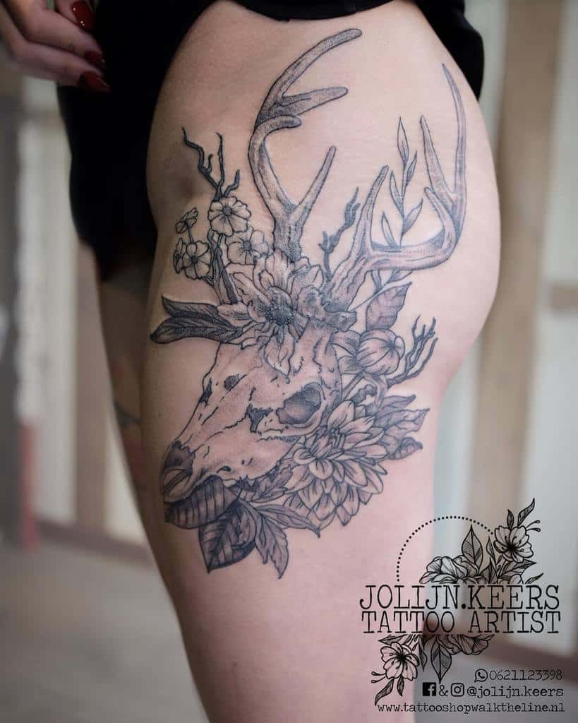 Intricate tattoo with a beautifully detailed deer skull adorned with flowers on an upper thigh