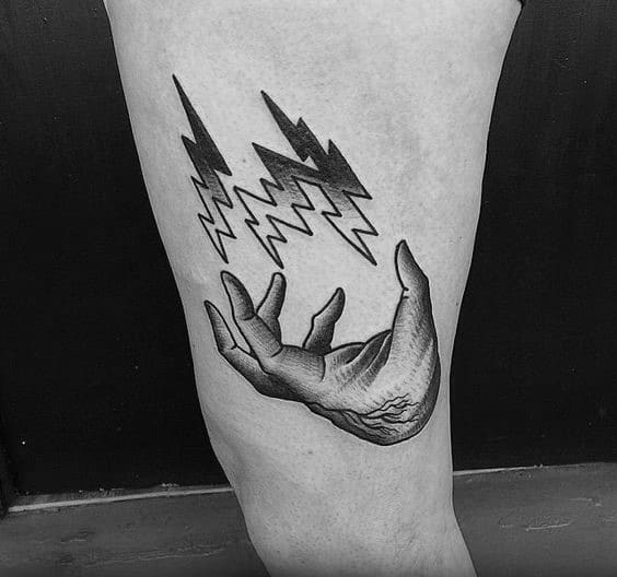 Black and white tattoo of a magician's hand releasing bold lightning bolts on the upper thigh