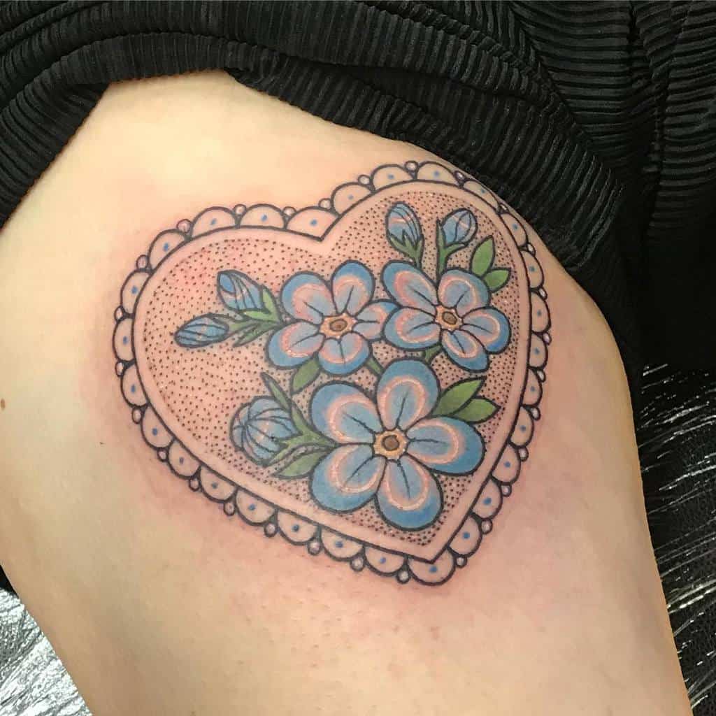 Heart-shaped tattoo with delicate blue forget-me-not flowers and a lace-like border