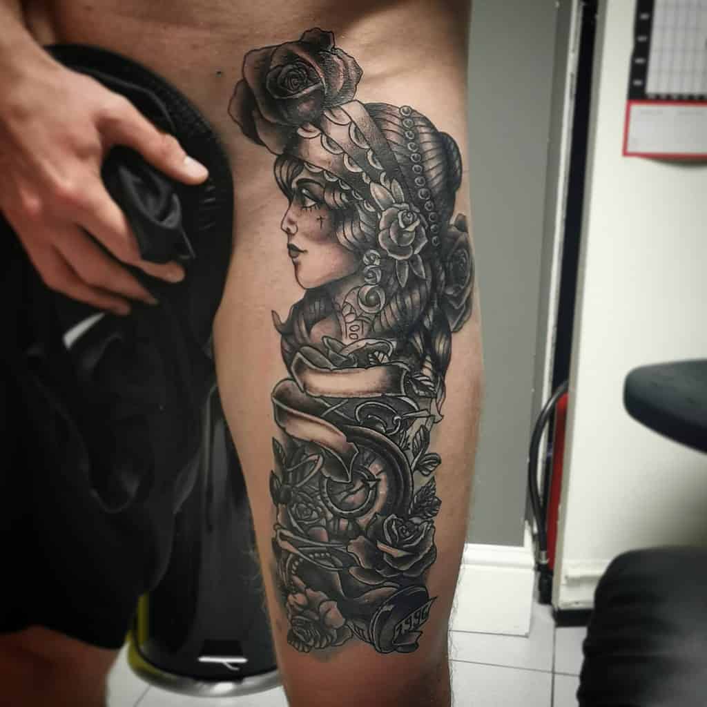 A gypsy-inspired thigh tattoo featuring a woman intertwined with roses and a clock in elegant black ink