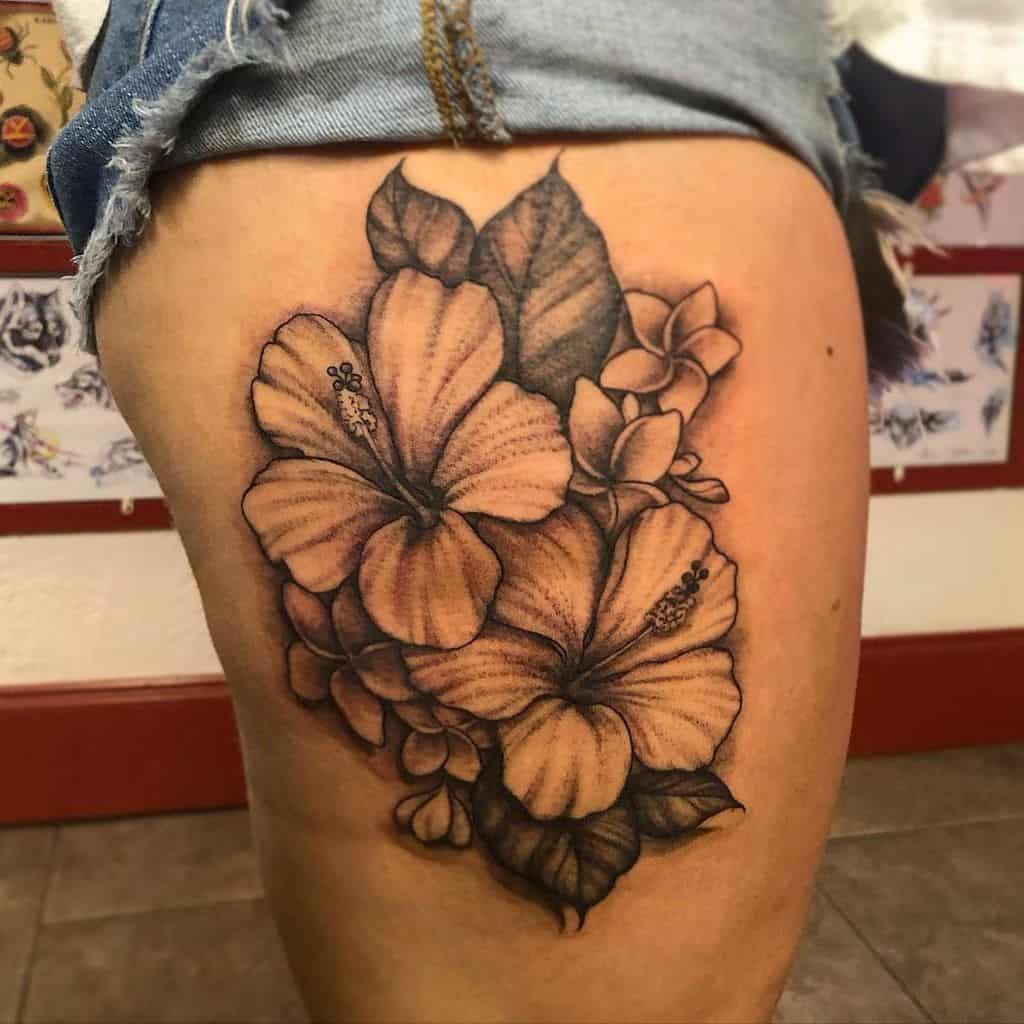 Thigh tattoo featuring large hibiscus flowers and leaves in black and gray