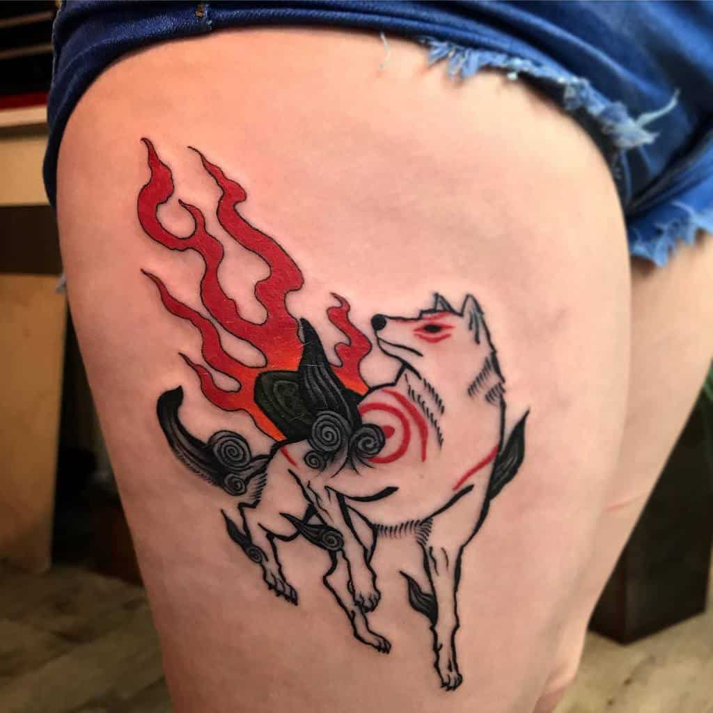 Tattoo of a stylized wolf with red flames and black swirling patterns on a thigh