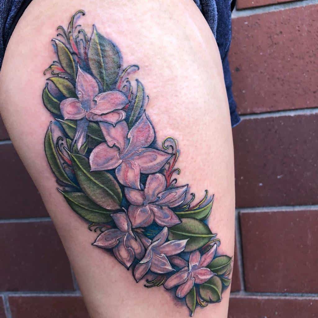 Floral tattoo with green leaves and pink flowers on a thigh