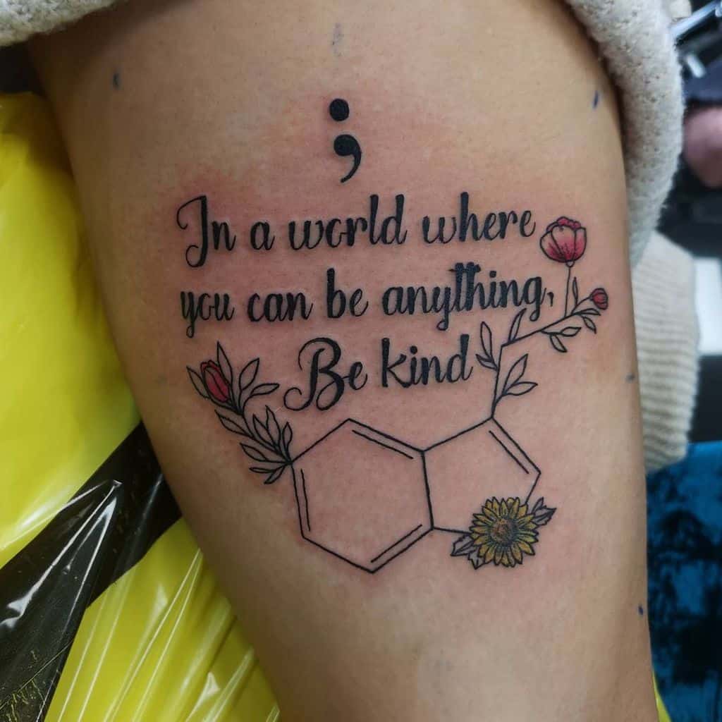 Tattoo of a semicolon, the text "Be kind," and subtle serotonin molecules intertwined with floral and geometric designs
