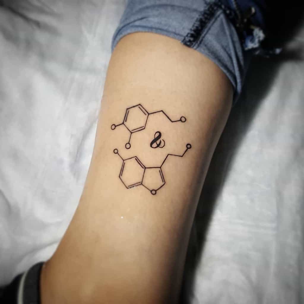 Serotonin molecule tattoo with an ampersand symbol in the center, placed on the thigh for a unique touch