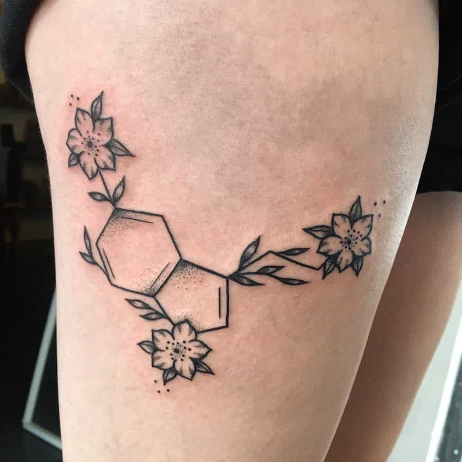 A stunning tattoo of a serotonin molecular structure surrounded by delicate flowers graces the person's thigh, symbolizing beauty and balance