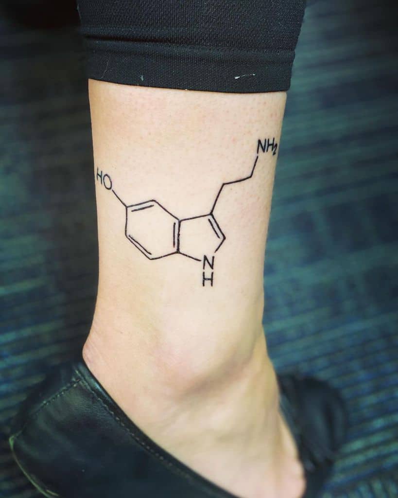 A minimalist serotonin tattoo graces the leg 