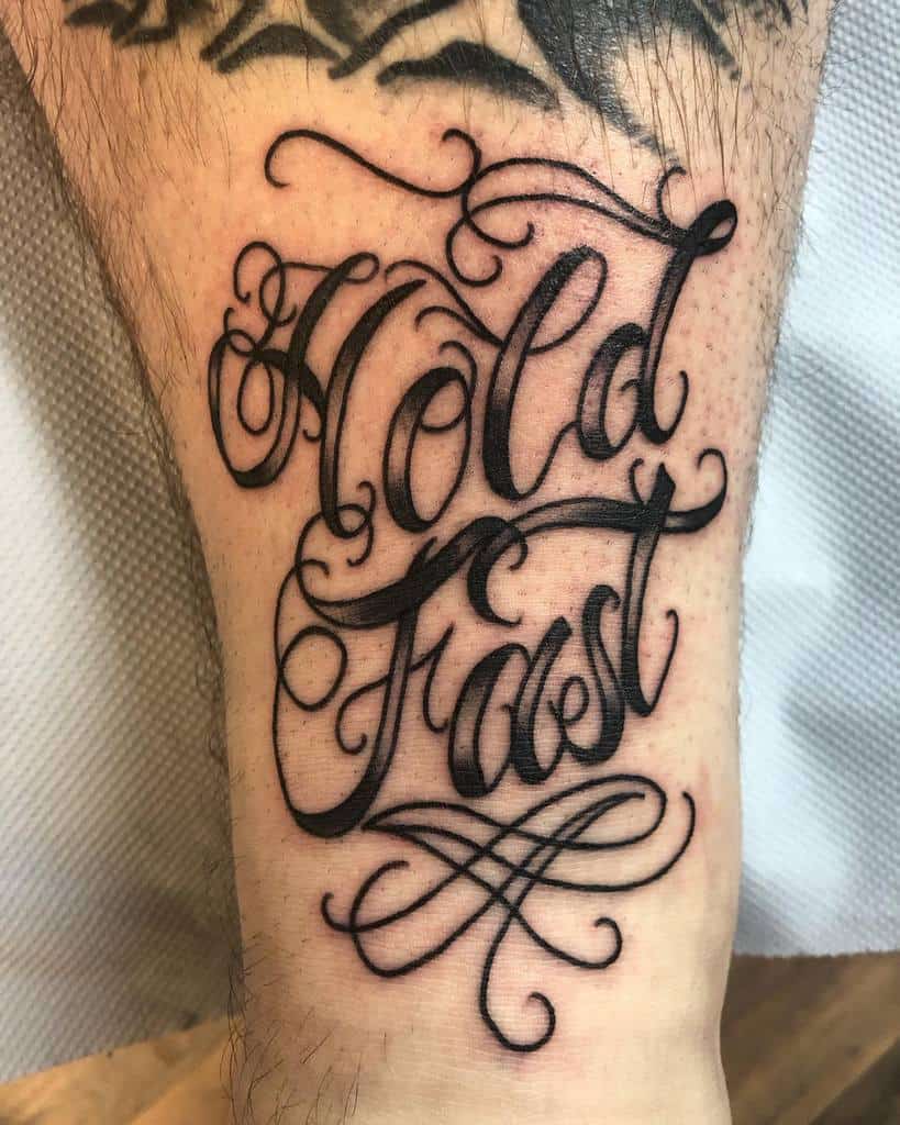 Tattoo on leg with cursive script reading "Hold Fast"