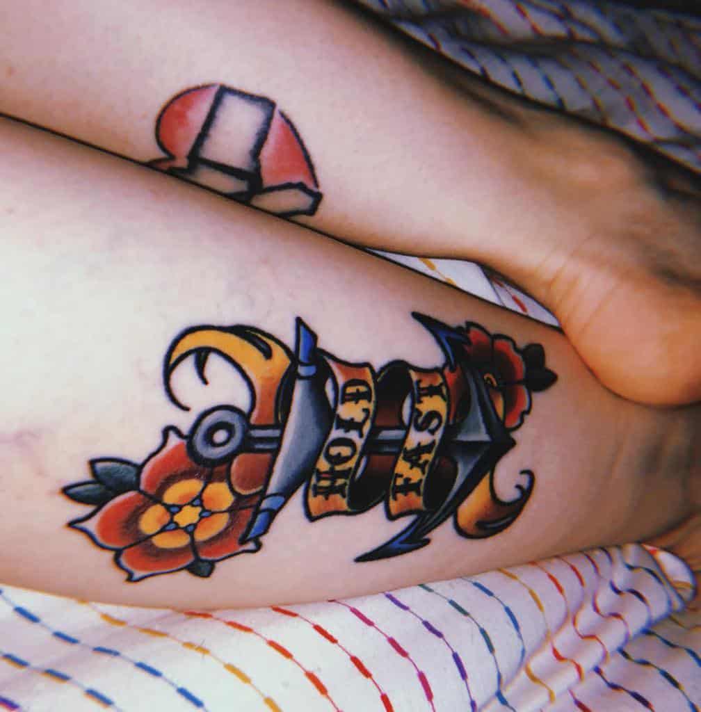 Colorful "Hold Fast" tattoo with flowers on a leg