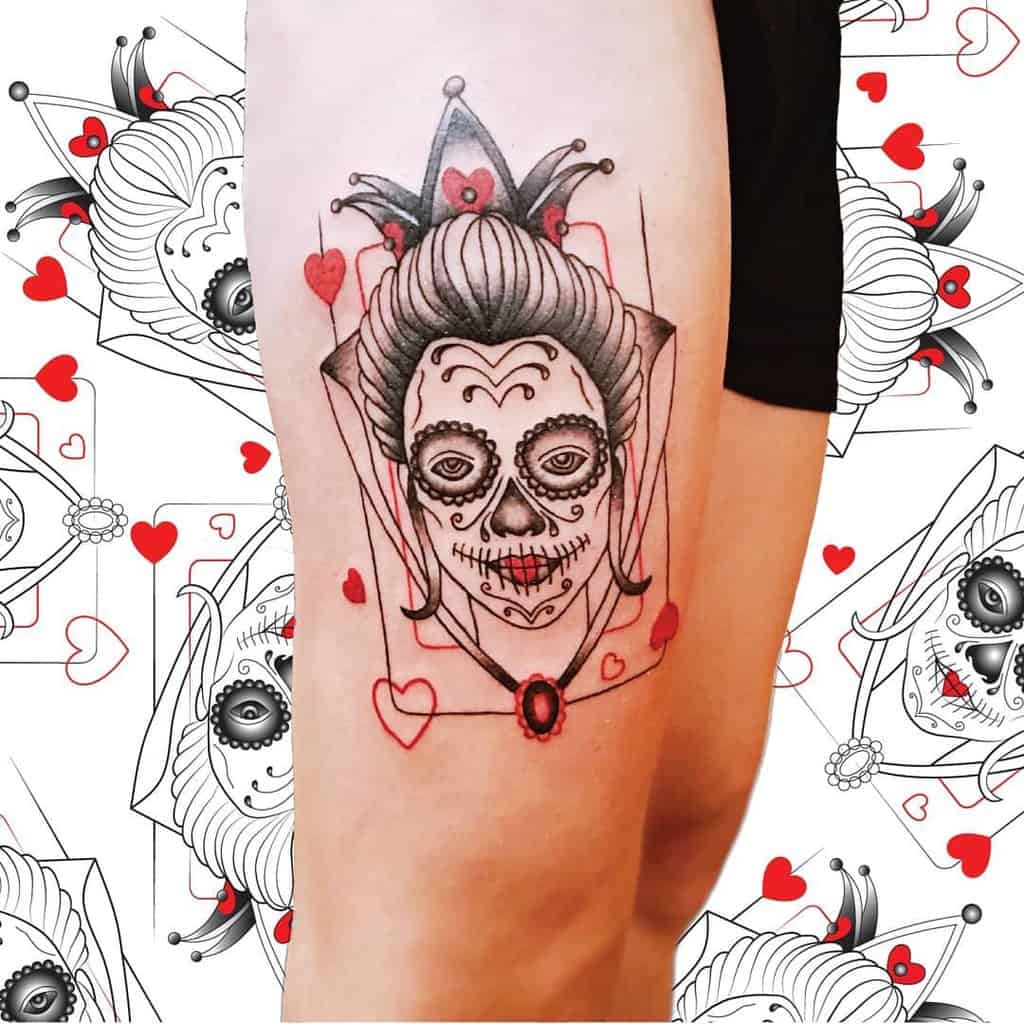 Tattoo of a skull-faced queen with hearts and a jester crown on a leg