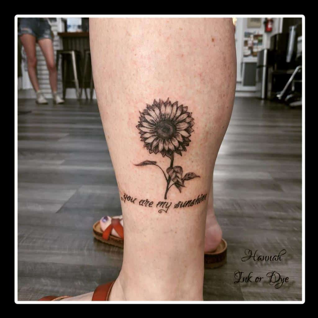 Leg tattoo of a sunflower with "you are my sunshine" text