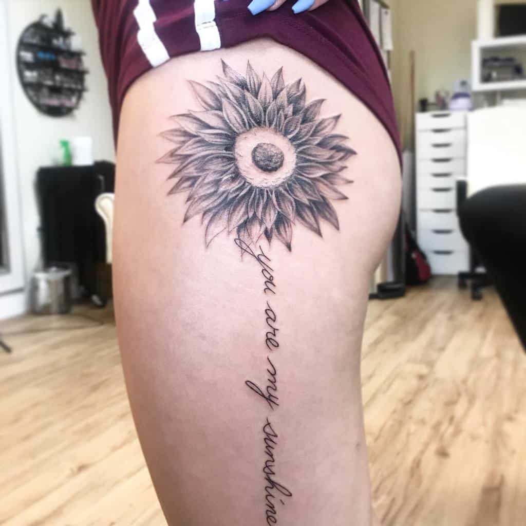 Sunflower tattoo with "you are my sunshine" text on a thigh