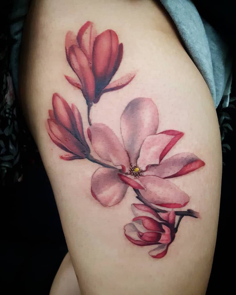 A delicate tattoo of pink magnolia flowers gracefully adorns an upper arm