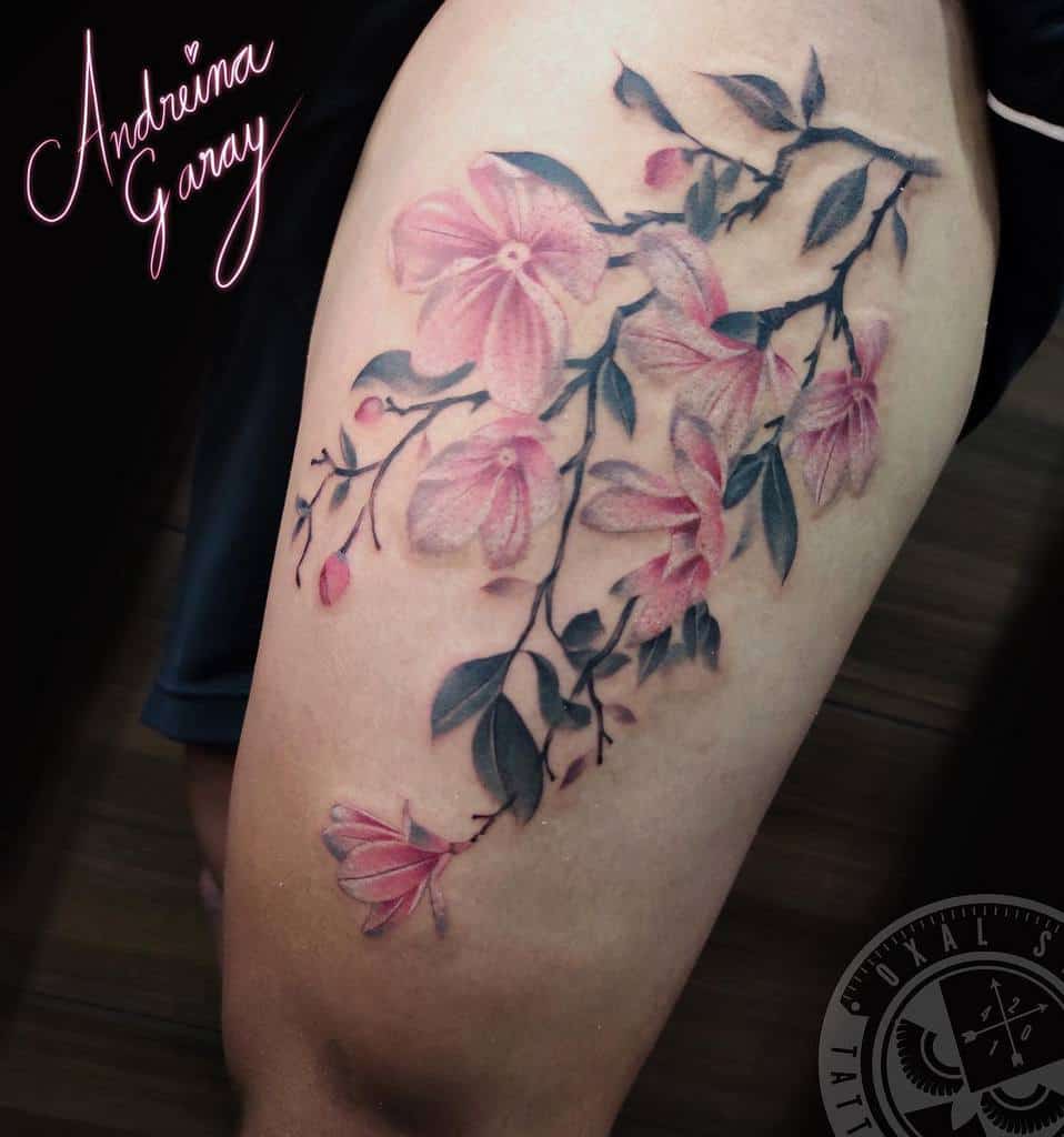 Tattoo of pink magnolia flowers and delicate leaves adorning an arm
