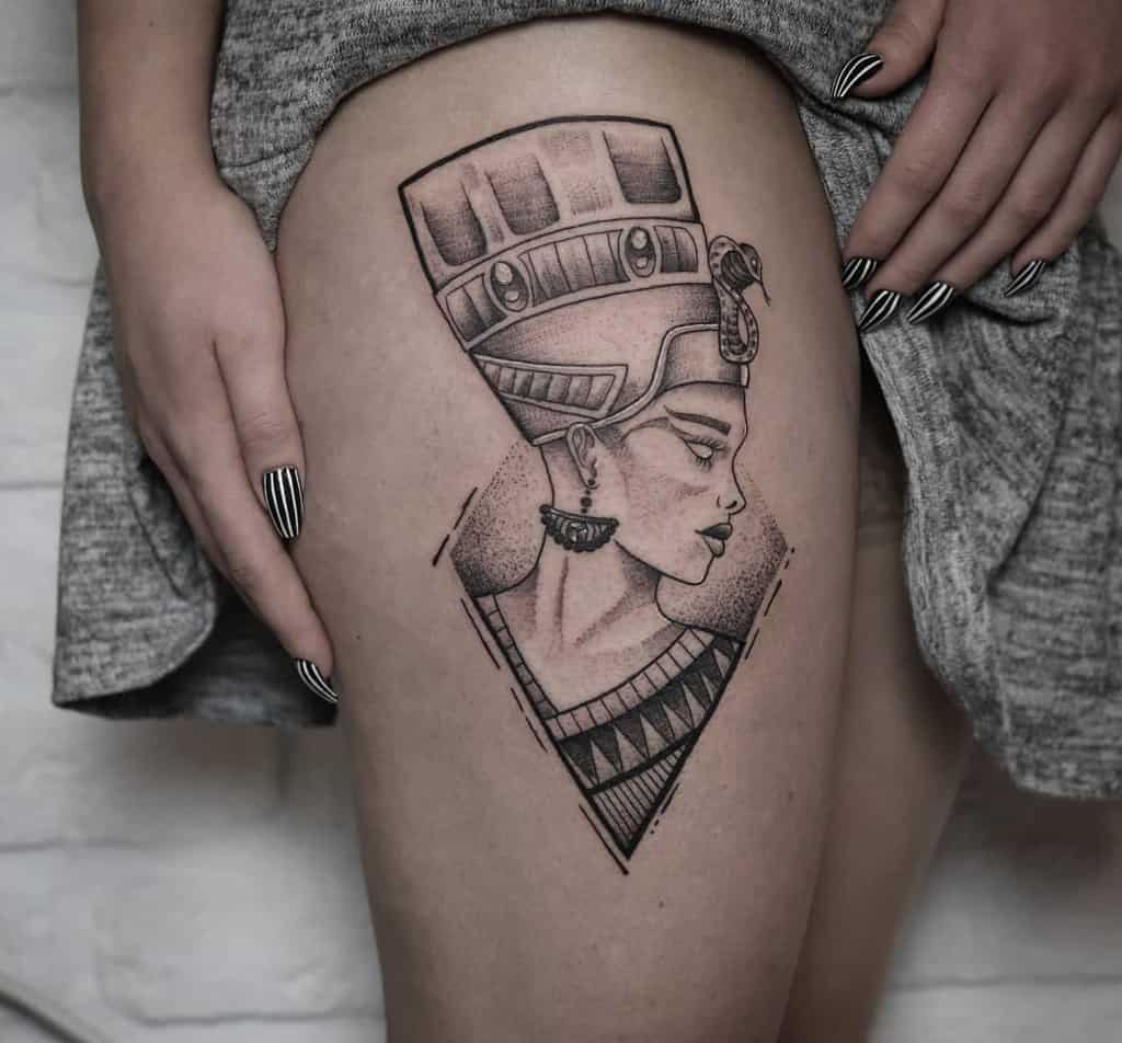 Stylized Nefertiti tattoo on the thigh with bold lines and geometric accents for a modern twist