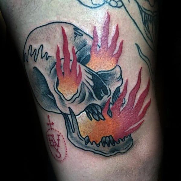 Tattoo of a skull with flames coming out of its eye sockets and mouth