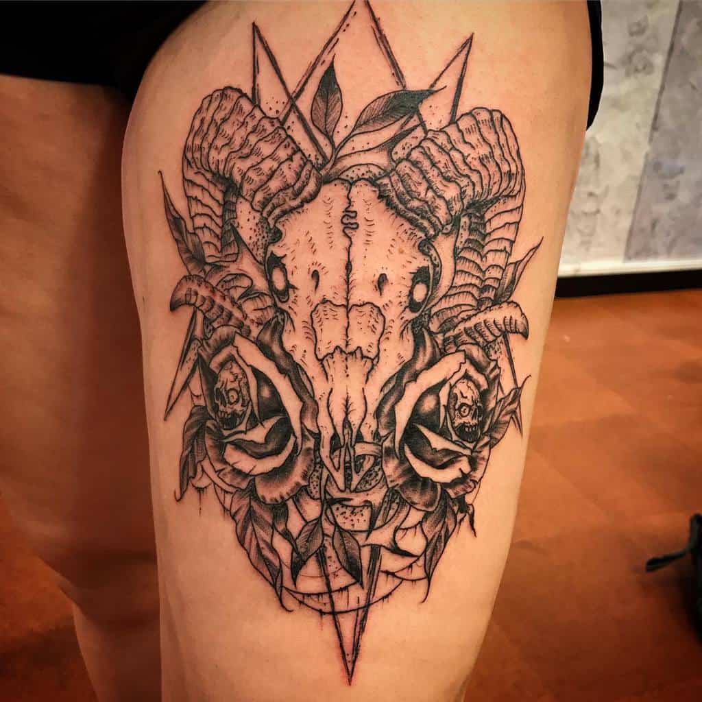 Tattoo of a ram skull surrounded by flowers and intricate geometric shapes on a thigh