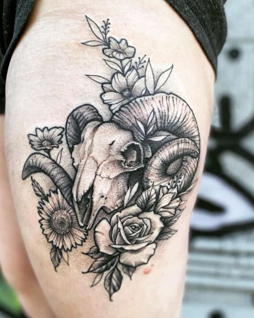 A stunning ram skull tattoo adorned with various flowers graces an upper thigh