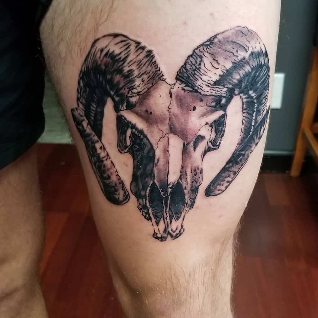 Tattoo of a ram skull with large curled horns elegantly inked on a person's thigh
