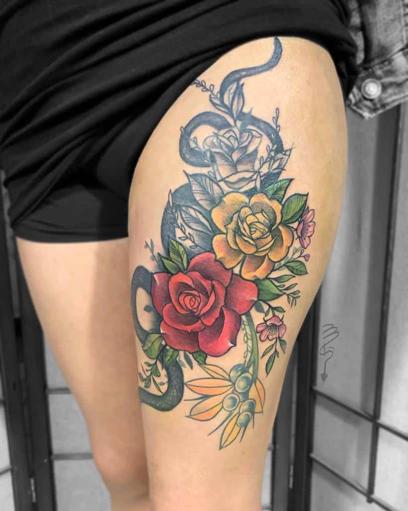 Colorful flower tattoo with red, yellow, and blue roses on a woman's upper thigh